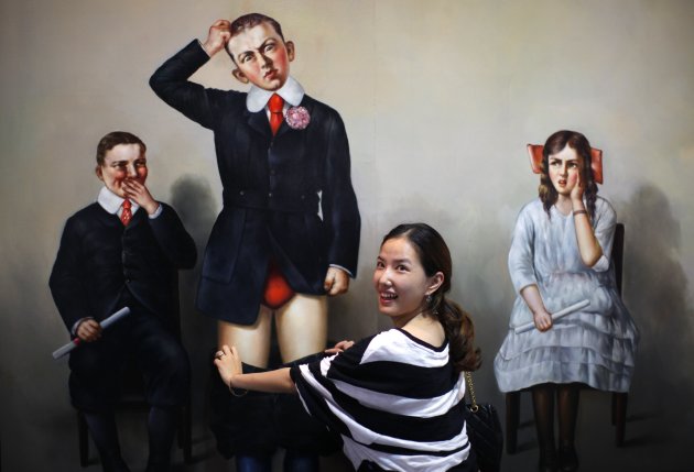 Woman poses for a photograph in front of a 3D painting at the 2012 Magic Art Special Exhibition in Hangzhou