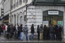 People line up at a currency exchange office in Geneva, Switzerland, Friday, Jan. 16, 2015. The Swiss National Bank (SNB) . Switzerland's central bank said Thursday it has scrapped a policy that limited how much the euro could fall against the Swiss franc, an unexpected decision that caused gyrations in financial markets. The move to ditch the policy — which ensured the euro did not fall below 1.20 francs — sent the euro plummeting a stunning 30 percent against the Swiss currency before it recovered somewhat. By later morning, it was down 13 percent at 1.04 francs. To keep the franc from surging in value once again, the national bank said it would also lower its average interest rate to minus 0.75 percent from minus 0.25 percent. Lower rates can help an economy and also weaken the national currency.(AP Photo/Keystone,Martial Trezzini)