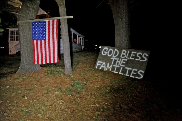 Across the street from the elementary school in Sandy Hook, Conn. neighbors hoisted an American flag and created a make-shift prayer for the deceased inside the school late Friday Dec. 14, 2012. (AP Photo/Robert Ray)