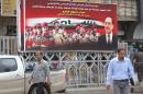 Iraqis walk past an election poster fronted by Iraqi Prime Minister Nuri al-Maliki (R) on March 25, 2014, in Baghdad, ahead of the parliamentary elections in April 2014