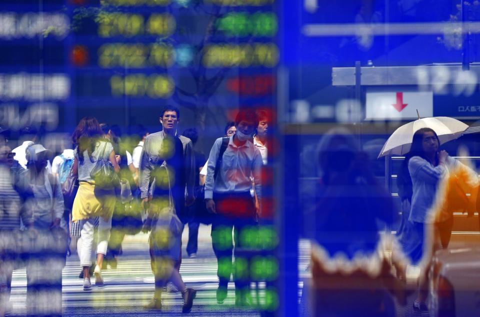 People are reflected on an electronic stock indicator of a securities firm in Tokyo, Monday, June 29, 2015.  Tokyo stocks plunged more than two...