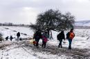 Migrants walk through the snow after crossing the Macedonian border into Serbia near the village of Miratovac on January 18, 2016