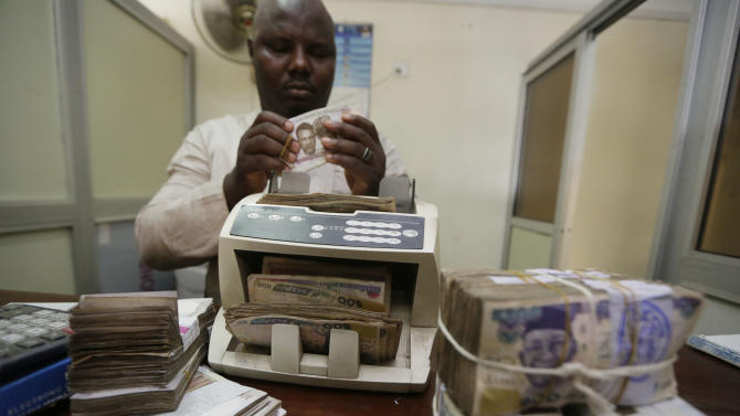 In this photo taken Tuesday Oct. 20, 2015, a money changer counts Nigerian naira currency at a bureau de change, where a dollar buys 222 naira compared to the official rate of 198, in Lagos, Nigeria. The IMF is pressing Nigeria to further devalue its naira currency amid uncertainty over the political and economic outlook for Africa&#39;s biggest oil producer and economy. Analysts said there&#39;s disappointment that President Muhammadu Buhari&#39;s long-awaited Cabinet list includes no economic stars. The naira has lost 25 percent of its value in the past year and the stock market has plummeted because of political uncertainty and halved prices for oil that provides most government revenue. (AP Photo/Sunday Alamba)