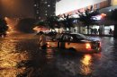 A taxi driver walks away after his car was stranded in a flooded street following a heavy rain in Beijing Saturday, July 21, 2012. China's government says the heaviest rains to hit Beijing in six decades. The torrential downpour Saturday night left low-lying streets flooded and knocked down trees. (AP Photo) CHINA OUT