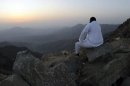 A man sits on the side of a hill waiting to see the new moon of Ramadan
