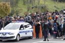 Slovenian policemen escort a group of migrants from a train towards a camp in Sentilj, Slovenia, Friday, Oct. 23, 2015. Thousands of people are trying to reach central and northern Europe via the Balkans but often have to wait for days in mud and rain at the Serbian, Croatian and Slovenian borders. (AP Photo/Petr David Josek)