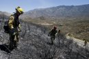 Firefighters look for hot spots as they walk through the scorched area on Friday, Aug. 9, 2013, near Banning, Calif. Southern California firefighters are facing another day of battle as they try to corral a wildfire that has destroyed 26 homes. (AP Photo/Jae C. Hong)