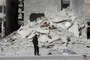 A rebel fighter carries a weapon as he inspects a site hit by what activists said was a barrel bomb dropped by forces loyal to Syria's President Bashar al-Assad in Aleppo's al-Saliheen district