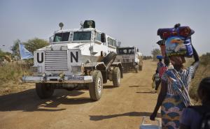 A United Nations armored vehicle passes displaced people …