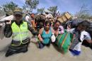 Colombian police help women carry their belongings as they cross the Tachira river on the border from Brisas de Barinitas, Venezuela into Colombia, August 25, 2015