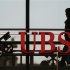 An employee walks past a logo of Swiss bank UBS in Zurich