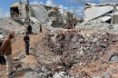 People walk past destroyed houses in the northern Syrian town of Azaz on April 21, 2013