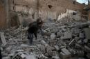 Men search for belongings at a site hit by missiles in the Douma neighborhood of Damascus
