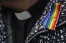 A priest wears a rainbow ribbon during a vigil against Anglican Homophobia outside the General Synod of the Church of England in London