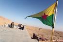 Kurdistan Workers Party (PKK) fighters guard a post flying the PKK flag as they participate in an intensive security deployment against Islamic State group militants in the town of Makhmur on August 21, 2014