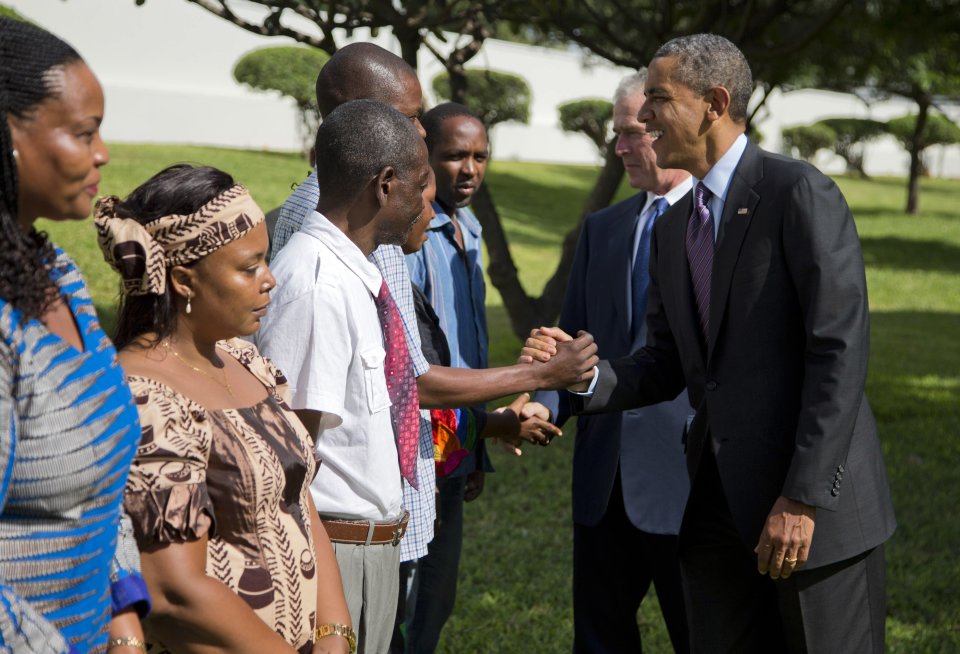 U.S. President Barack Obama, right, and former President George W. Bush shake hands with family members of victims of the U.S. Embassy bombing during a wreath laying ceremony at the U.S. Embassy on Tuesday, July 2, 2013, in Dar Es Salaam, Tanzania. The president is traveling in Tanzania on the final leg of his three-country tour in Africa. (AP Photo/Evan Vucci)