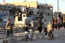 Iraqis stand watching as an armoured vehicle carrying armed militants in Fallujah, on March 20, 2014