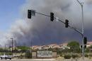 Smoke plumes rise behind the Marine Corps Camp Pendleton entrance Friday, May 16, 2014, in Oceanside, Calif. San Diego County officials said Friday five wildfires have been 100 percent contained. Still, crews were focusing efforts on two large fires — one in the city of San Marcos and two blazes at the Marine Corps' Camp Pendleton. (AP Photo/Gregory Bull)