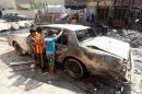 Iraqi children inspect a burnt-out car at the site of a car bomb attack in Baghdad on September 16, 2013