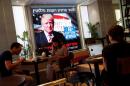 People dine at a coffee shop as an image of newly elected U.S. President Donald Trump is displayed on a monitor in Tel Aviv, Israel