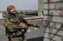 A Ukrainian serviceman checks an area as he stands on a roof in Avdeyevka
