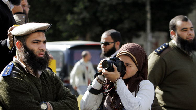 FILE - In this Monday, March 4, 2013, file photo, a journalist take pictures of Egyptian Salafi Muslims, unseen, during a protest in support of bearded police officers who were prevented from carrying out their work in the interior ministry, in front of the Shura Council, the upper house of Parliament, in Cairo, Egypt. Amid Egypt's multiple woes under an Islamist-dominated administration, religion is not the political selling point it once was among Egyptians, one factor fueling planned weekend protests calling for Morsi's fall. (AP Photo/Amr Nabil, File)