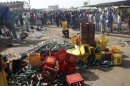 Passanti davanti al luogo dell'esplosione di una bomba in un mercato di Bauchi, nella Nigeria settentrionale
