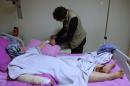 In this picture taken with a mobile phone on Saturday, Oct. 24, 2015, a Syrian boy Abdulhamid Khanfoura, 16, background, helps his wounded mother Zahra Khanfoura, 48, who was burned by a Russian airstrike that hit her house in the central Syrian village of Habeet, as she lies on her hospital bed in the southern city of Kadirli, Turkey. Zahra's granddaughter Raghad was among dozens of civilians who activists say have been killed in the Russian air campaign in Syria, which Moscow says is aimed at crushing the Islamic State group and other Islamic militants. (AP Photo/Hussein Malla)