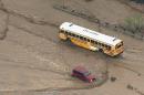 In this image made from a video provided by ABC15 TV, a school bus navigates a flooded road north of Phoenix, Tuesday, Aug. 19, 2014. It was not known if there were children aboard the bus at the time. The area was flooded after several inches of rain pummeled the state. (AP Photo/ABC15 TV)