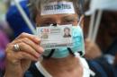 A protester holds her nurse identification card during a demonstration in support of Spanish nurse Teresa Romero infected with the deadly Ebola virus in Madrid on October 11, 2014