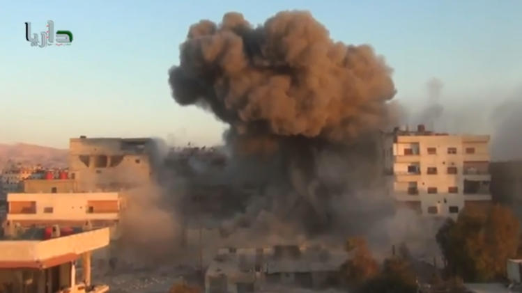 In this image taken from video obtained from the Shaam News Network, which has been authenticated based on its contents and other AP reporting, smoke billows amid buildings at a bomb explosion in Daraya, a countryside of Damscus, Syria, Tuesday, Oct. 15, 2013. Syrian warplanes bombed several rebel-held areas Tuesday and opposition fighters fired mortar rounds and homemade rockets at Damascus on the first day of a major Muslim holiday, activists said. (AP Photo/Shaam News Network via AP Video)