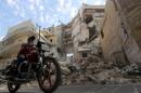 A boy rides a motorcycle through a damaged street in Old Aleppo, Syria