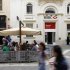 People sit in an outdoor coffee shop in front of an HSBC bank branch in Valletta