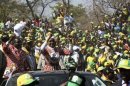 Zimbabwe President Robert Mugabe and his wife Grace wave during an election rally in Chinhoyi