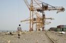 Worker walk on debris following an air strike on Yemen's Hodeida port