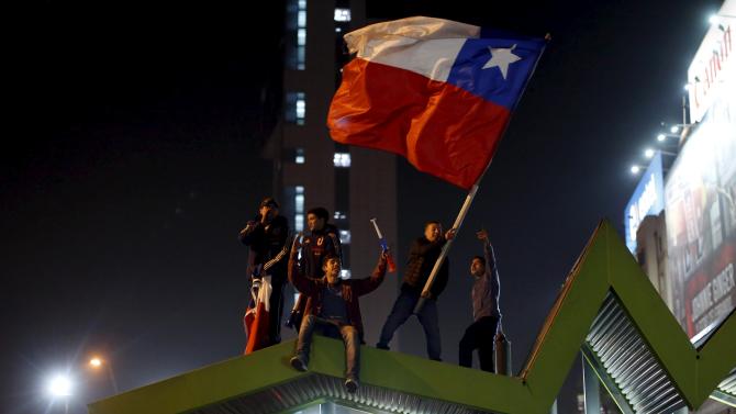 Fans wave a Chilean national flag as they celebrate after Chile&#39;s victory over Uruguay in their Copa America 2015 quarter-finals soccer match in Santiago