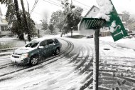A vehicle makes its way at the snow-covered intersection of Autumn and Grove Streets in Lodi, N.J., following a rare October snowstorm that hit the region, Saturday, Oct. 29, 2011. (AP Photo/Julio Cortez)