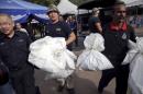 Forensic policemen carry body bags with human remains found at the site of human trafficking camps in the jungle close the Thailand border after they brought them to a police camp near Wang Kelian in northern Malaysia