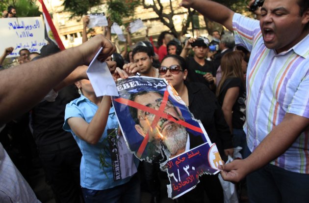 Egyptian protesters burn a poster with the photo of Egyptian President Mohammed Morsi with Arabic that reads, " Rebel, Muslim Brotherhood will fall on June 30 at the Itihadiya Palace," in front of the Culture Ministry in Cairo, Egypt, Tuesday, June 11, 2013. Fears that protests on June 30 will result in bloodshed were heightened when opposition protesters nabbed at least six pro-Morsi supporters outside the Culture Minister’s office in Zamalek on Tuesday. An Associated Press reporter witnessed the protesters beating bearded men with their fists, kicking them and stoning them as they outnumbered riot police trying to intervene. (AP Photo/Khalil Hamra)
