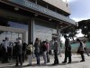 People wait in line to enter a branch of the Bank of Cyprus in Nicosia, Thursday, March 28, 2013. Banks in Cyprus reopened to customers for the first time in nearly two weeks Thursday, albeit with strict restrictions on transactions, after being closed to prevent people withdrawing all their savings during the country’s acute financial crisis. Large lines had formed outside the banks ahead of the opening of banks for six hours from noon. (AP Photo/Petros Giannakouris)