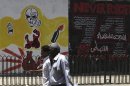 People walk past graffiti with Arabic text that reads "Art of resistance, Revolution" near Tahrir Square in Cairo