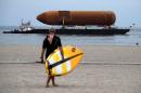 A paddle boarder makes his way to the water as the space shuttle fuel tank ET-94 arrives by barge in Marina del Rey, California