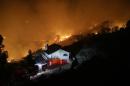 A wildfire burns near a home on Wednesday, May 14, 2014, in San Marcos, Calif. Flames engulfed suburban homes and shot up along canyon ridges in one of the worst of several blazes that broke out Wednesday in Southern California during a second day of a sweltering heat wave. (AP Photo)