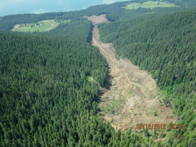 The Johnsons landing landslide is shown in this Thursday July 12, 2012 photo provided by Emergency BC. Four people are still unaccounted for nearly 24 hours after a wall of rock, mud and trees cascaded down the side of a mountain above the shores of Kootenay Lake, tearing through the tiny community of Johnsons Landing, about 70 kilometres northeast of Nelson. At least three homes in the southeastern B.C. hamlet are engulfed by the muck, which is unstable and shifting, prompting searchers to call off rescue efforts at least once on Thursday afternoon. Emergency crews met at dawn Friday to consider the most efficient and effective way to search the massive mudslide for possible victims. (AP Photo/Emergency BC via The Canadian Press) HANDOUT PHOTO; ONE TIME USE ONLY; NO ARCHIVES; NOT FOR RESALE