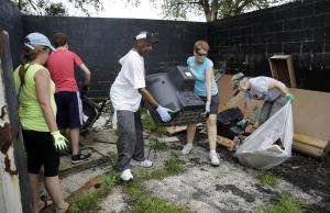 Volunteers help to cleanup trash behind a business …