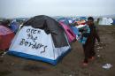 Refugees walk past tents near the Greek-Macedonian border, in the northern Greek village of Idomeni, on Monday, Feb. 29, 2016. Some 7,000 migrants, including many from Syria and Iraq, are crammed into a tiny camp at the Greek border village of Idomeni, and hundreds more are arriving daily. (AP Photo/Petros Giannakouris)