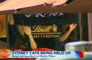 This image taken from video shows people holding up what appeared to be a black flag with white Arabic writing on it, inside a cafe in Sydney, Australia Monday, Dec. 15, 2014. A hostage siege in Sydney that began Monday morning and ended with a police raid 16 hours later unfolded before the world on Monday. (AP Photo/Channel 7 via AP Video) AUSTRALIA OUT