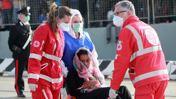 A woman is helped to disembark from a ship following an operation to rescue migrants at sea, part of the Frontex-coordinated Operation Triton, on May 6, 2015 in Messina harbour