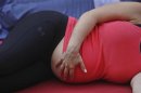 A pregnant woman touches her stomach as people practice yoga on the morning of the summer solstice in New York's Times Square June 20, 2012. REUTERS/Shannon Stapleton