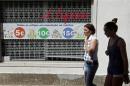 Women walk past a shop window announcing sale prices along a street in Mafra, north of Lisbon